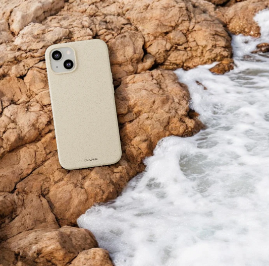 An eco-friendly phone cover placed on rocks on the beach.