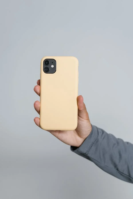 Smartphone with a peach-colored compostable phone case on a wooden table.